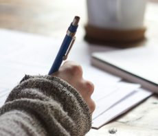 Hand schreibt mit Stift auf Papier, Symbol für technische und inhaltliche Optimierung